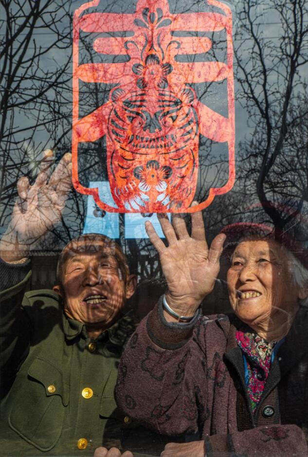臘月里，霍州市師莊鄉(xiāng)馮南垣村村民師榮光(左)在災(zāi)后重建的新家里貼窗花。(霍州市委宣傳部供圖)