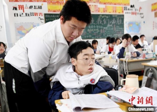 朱金祥(左)把鐘華強(qiáng)放到課堂座位上后，都要把他擺正好，確認(rèn)安全后才回到自己的座位上。 卓忠偉 攝