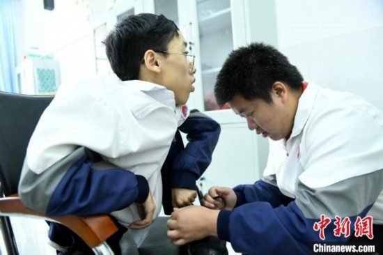 江西省南康中學(xué)北校區(qū)的高三學(xué)生朱金祥(右)正在給鐘華強(qiáng)(左)系好鞋帶。 卓忠偉 攝