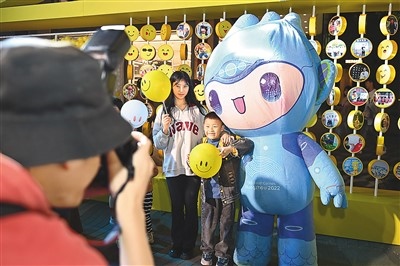 5月7日，在浙江省杭州市湖濱步行街“3D笑臉墻”前，攝影師為游客與杭州亞運(yùn)會(huì)吉祥物之一“宸宸”拍攝合影。