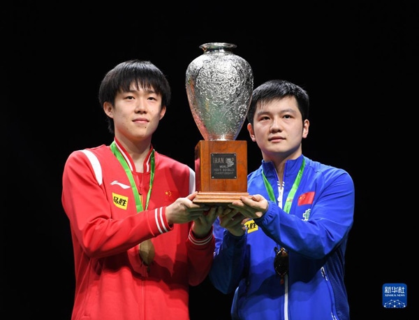 5月27日，樊振東（右）/王楚欽在頒獎(jiǎng)儀式上高舉獎(jiǎng)杯慶祝。當(dāng)日，在南非德班進(jìn)行的2023年世界乒乓球錦標(biāo)賽男雙決賽中，中國(guó)組合樊振東/王楚欽以3比0戰(zhàn)勝韓國(guó)組合張禹珍/林鐘勛，奪得冠軍。新華社記者 李亞輝攝