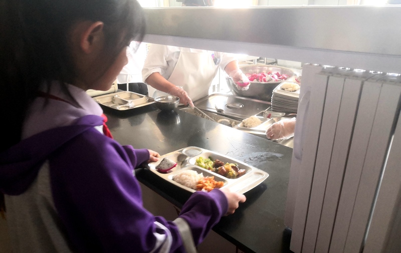 伊金霍洛旗第一小學(xué)學(xué)生正在打飯，今天的飯菜是三菜一湯外加水果，學(xué)生可以多次盛取，吃飽為止。人民網(wǎng)記者 孫博洋攝
