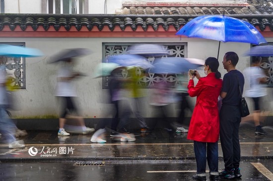 6月7日，在浙江省2023年普通高校招生考試鎮(zhèn)海中學考點，家長冒雨目送子女進入考場。人民網(wǎng) 章勇濤攝