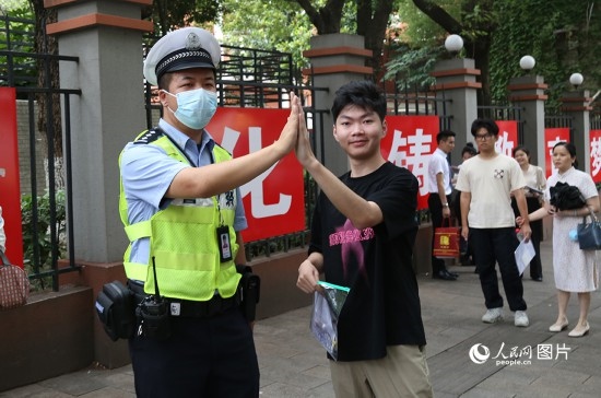 6月7日8時許，武漢中學考點門口，交警在維護秩序，并?？忌鸢耦}名。人民網(wǎng)記者 肖璐欣攝