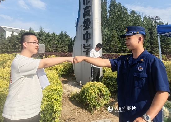 6月7日，遼寧營口老邊區(qū)消防救援大隊的消防員為高考學子加油助威。人民網(wǎng)記者 尹柏寒攝