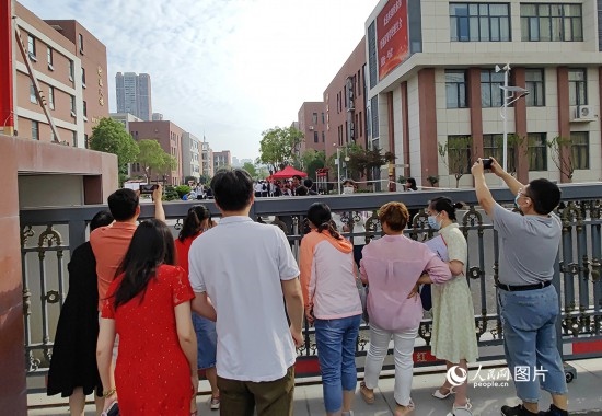 6月7日，武漢市第三中學考點，考生進場后，家長在柵欄外用手機拍攝自己的孩子。人民網(wǎng)記者 郭婷婷攝