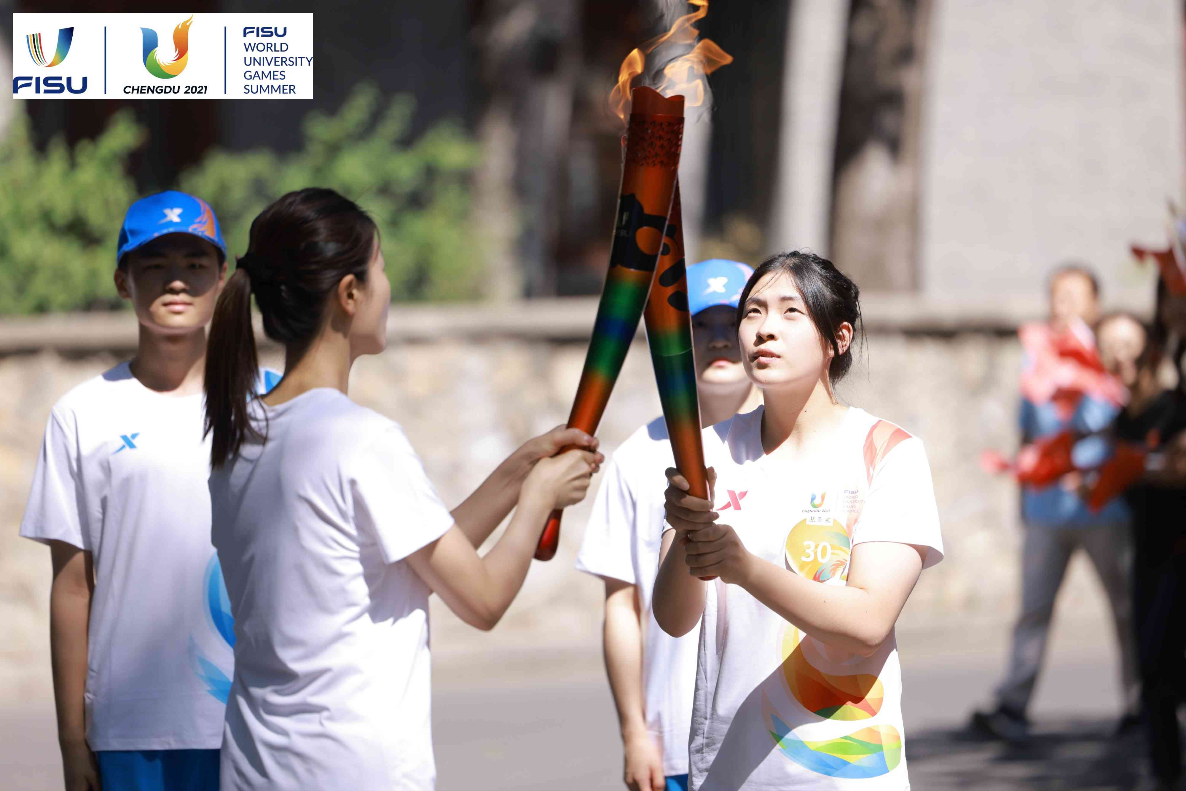 兩名大運(yùn)會火炬手進(jìn)行火炬?zhèn)鬟f。 圖片來源：成都大運(yùn)會執(zhí)委會供圖