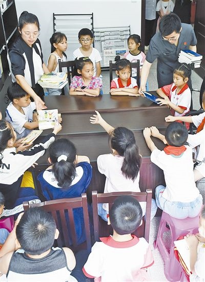  圖④：法院干警為留守兒童發(fā)放暑假讀物。