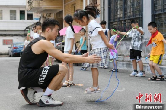 圖為大學(xué)生志愿者在教孩子們學(xué)跳繩。廖光福 攝