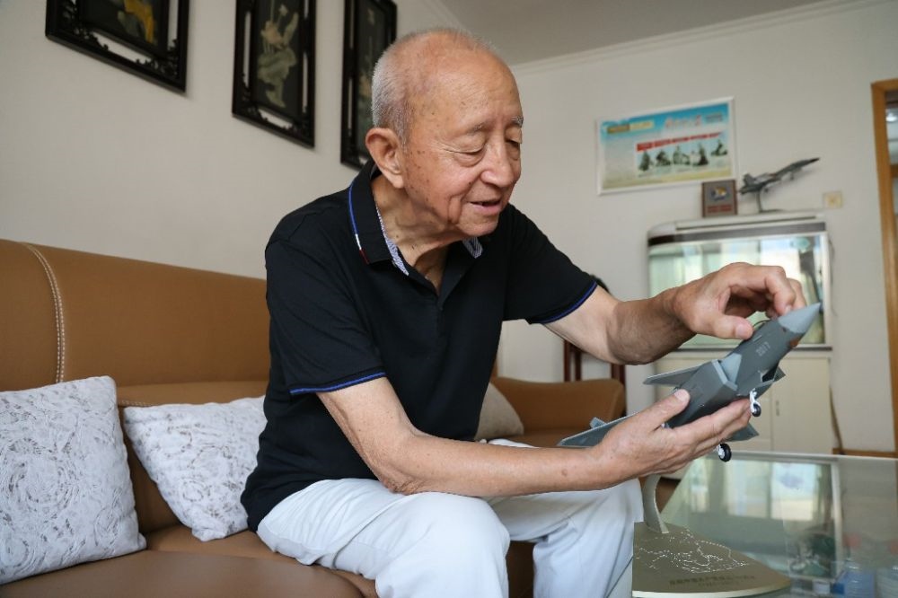 ↑2023年7月24日，新中國第一代飛行員陶偉在家中擦拭殲-20飛機(jī)模型。新華社發(fā)（張瑞 攝）
