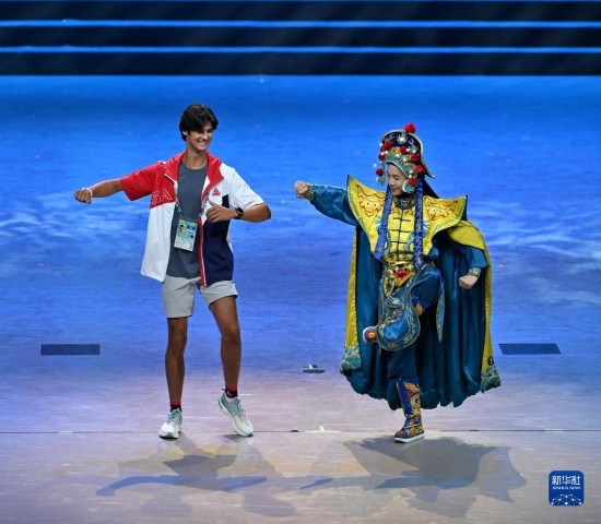 7月29日，美國運(yùn)動員杜恩（左）在聯(lián)歡會現(xiàn)場與川劇演員互動。新華社記者 蔡湘鑫 攝