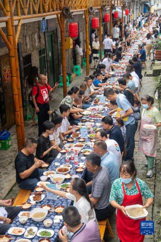 7月29日，在重慶市綦江區(qū)安穩(wěn)鎮(zhèn)，人們在“苗家伏羊節(jié)”上吃長桌宴。新華社記者 唐奕 攝
