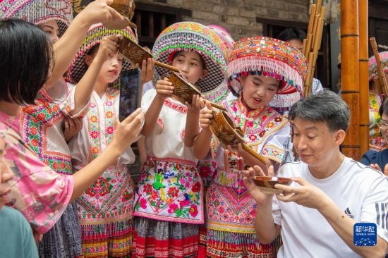 7月29日，在重慶市綦江區(qū)安穩(wěn)鎮(zhèn)，當地居民在“苗家伏羊節(jié)”上用傳統(tǒng)習俗向游客表達祝福。新華社記者 唐奕 攝
