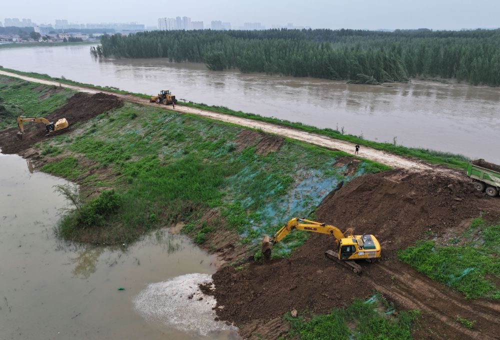 工人操作機(jī)械在白溝河左堤白溝新城高橋村段進(jìn)行除險(xiǎn)加固作業(yè)（8月4日攝，無人機(jī)照片）。新華社記者 朱旭東 攝