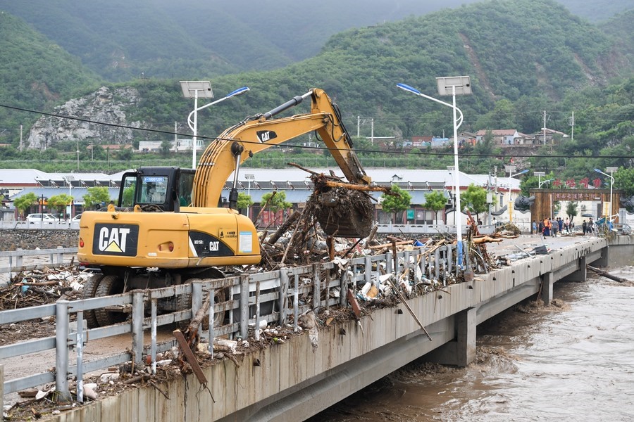 8月1日，在北京市門頭溝區(qū)水峪嘴村村口，一臺挖掘機(jī)在清理阻斷橋梁交通的雜物。目前該條道路已經(jīng)疏通完成。新華社記者 鞠煥宗 攝