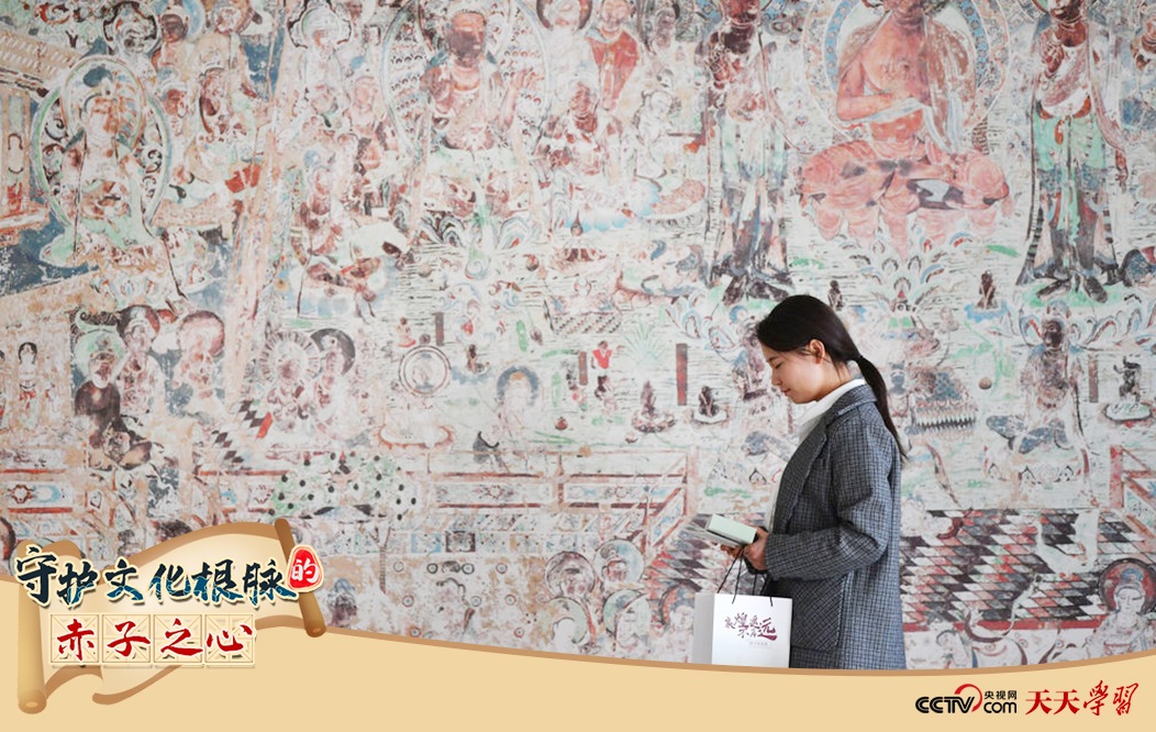 2023年4月25日，敦煌研究院文物數(shù)字化保護團隊創(chuàng)意營銷人員廖雪婷從一幅高保真復(fù)制壁畫前走過。
