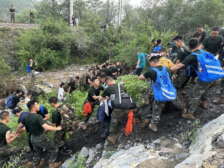 8月2日，Z180次受困列車的旅客在武警北京總隊機動第三支隊官兵的幫助下徒步前往轉(zhuǎn)運客車（手機照片）。新華社記者 王艷剛 攝