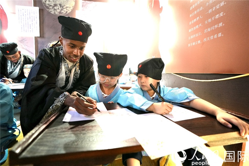 圖為選手與同學們一起寫書法。人民網(wǎng) 盧鵬宇攝