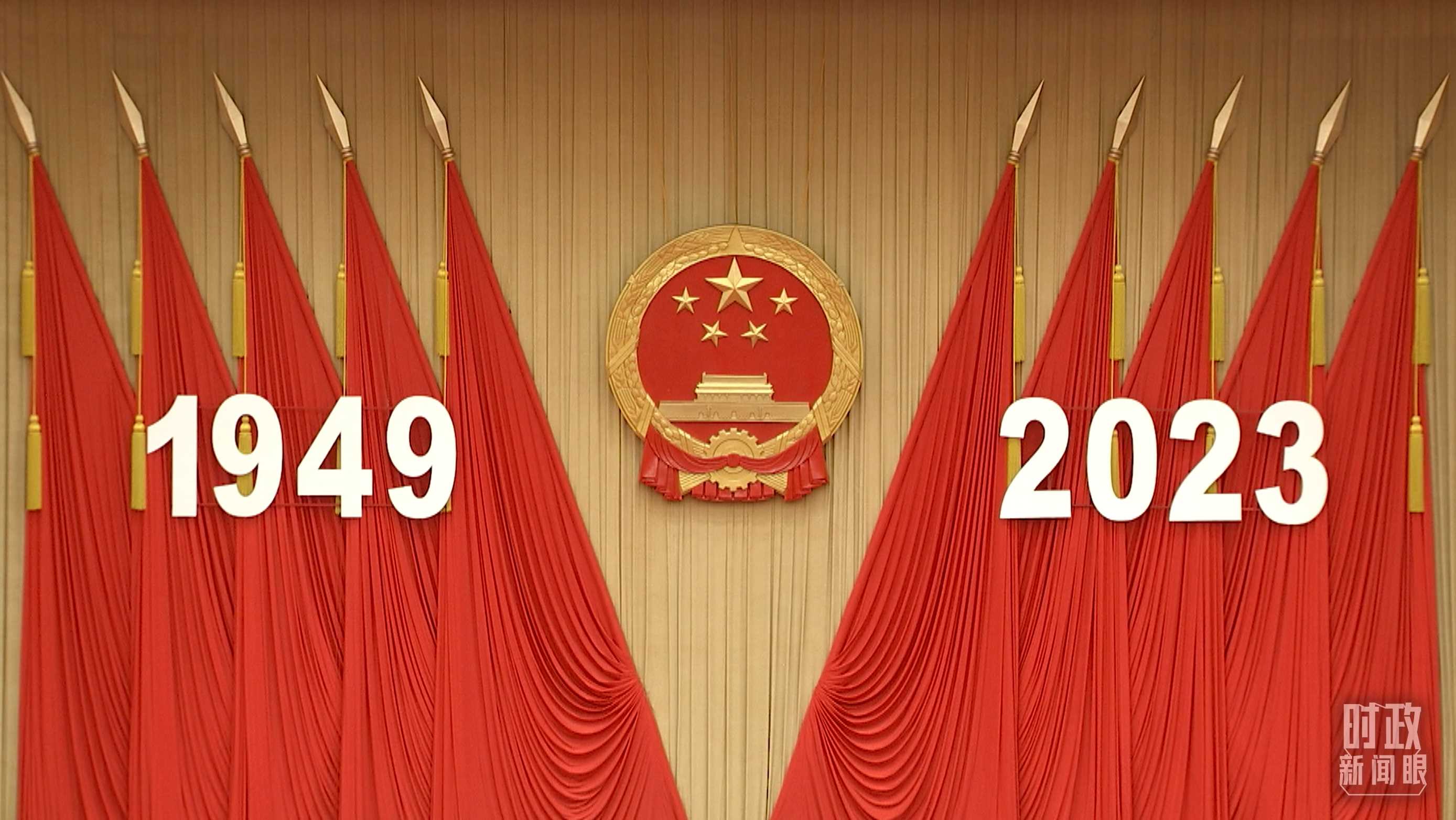 △人民大會(huì)堂宴會(huì)廳內(nèi)，主席臺(tái)上方高懸著莊嚴(yán)的國徽，“1949－2023”大字年號(hào)在鮮艷的紅旗映襯下格外醒目。