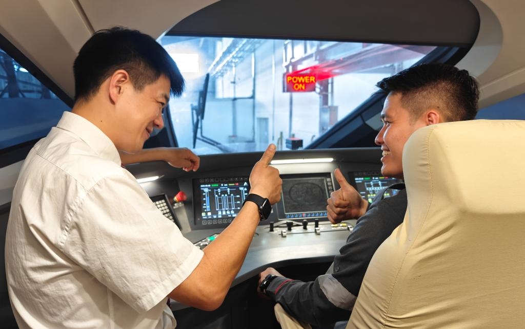 8月25日，在印度尼西亞萬隆的雅萬高鐵德卡魯爾動(dòng)車所內(nèi)，中國師傅穆振（左）在向印尼火車司機(jī)塞蒂亞萬講解動(dòng)車組出庫前的上電作業(yè)。