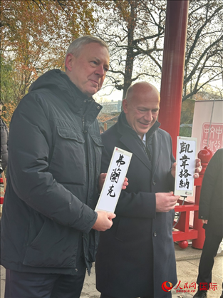 柏林市長韋格納（右）、動(dòng)物園監(jiān)事會(huì)主席布魯克曼（左）手持中國文化中心工作人員現(xiàn)場手書的中文名字。人民網(wǎng)記者 徐馨攝
