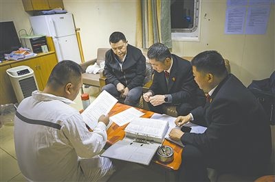 圖②：法官向船長講解相關(guān)法律規(guī)定，查看船舶資料，并與船方辦理扣押船舶的手續(xù)。