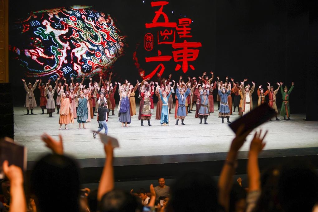 2023年7月31日，新疆和田地區(qū)新玉歌舞團在烏魯木齊京劇院演出舞劇《五星出東方》后和觀眾互相揮手致意。這場演出是第六屆中國新疆國際民族舞蹈節(jié)的參演劇目之一，曾榮獲國家“文華獎”等。新華社記者 郝昭 攝