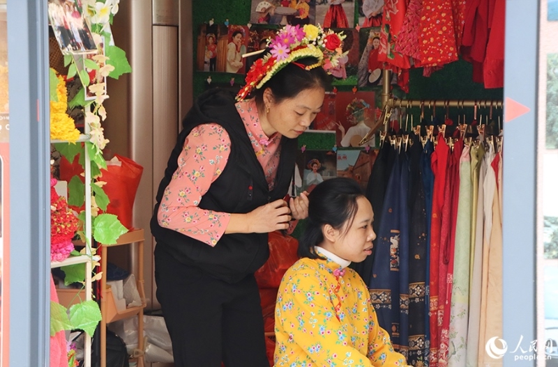 泉州府文廟附近，一名店主正為過(guò)路游客梳理頭發(fā)以佩戴“簪花圍”。人民網(wǎng) 黃東儀攝