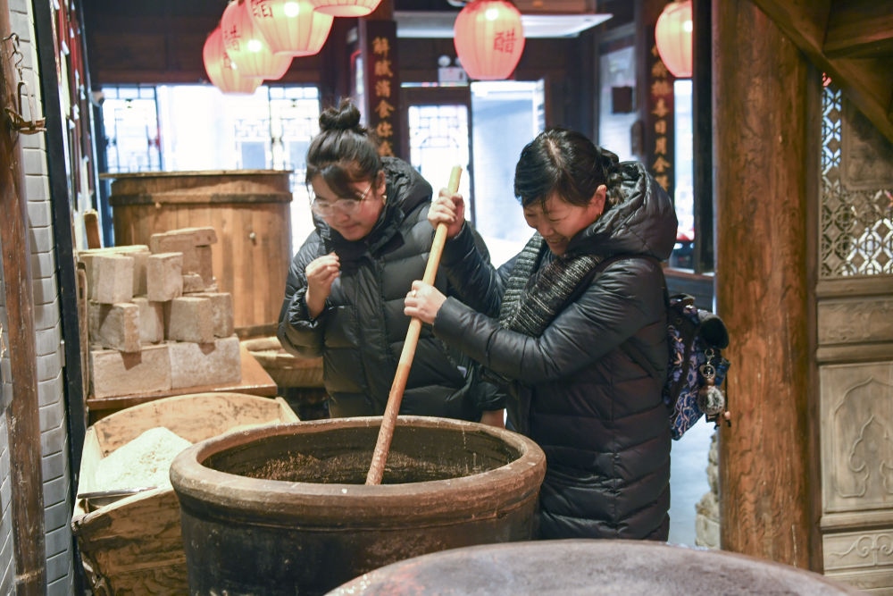 游客在平遙古城東湖老醋坊內(nèi)體驗(yàn)陳醋發(fā)酵打耙（2022年1月28日攝）。新華社發(fā)（梁生仁攝）