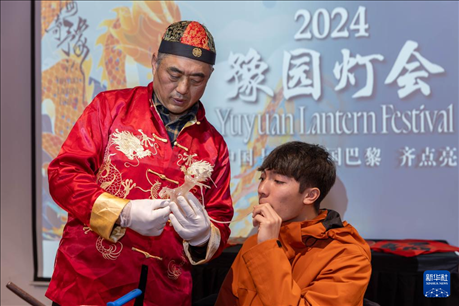 1月28日，在上海豫園舉行的民俗活動(dòng)上，美國(guó)馬斯卡廷中學(xué)學(xué)生在非遺傳承人的指導(dǎo)下吹糖偶。 新華社記者 王翔 攝