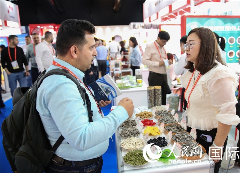 圖為一家中國(guó)干果參展企業(yè)代表與采購(gòu)商洽談。人民網(wǎng) 塔里克·易卜拉欣攝