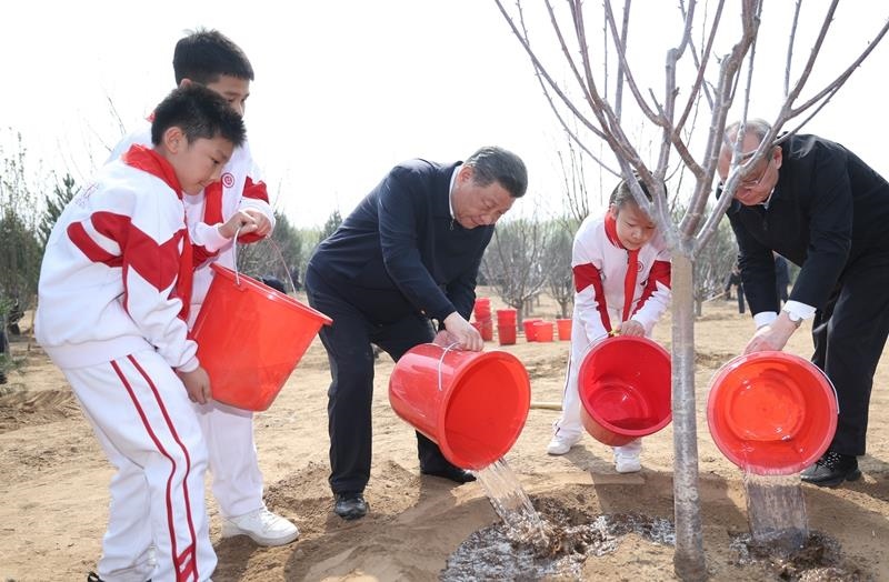 2024年4月3日，習(xí)近平總書記同少先隊(duì)員一起給剛栽下的樹苗澆水。