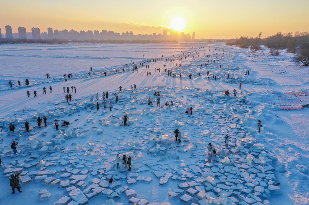 2024年1月7日，在封凍的松花江哈爾濱段，游客在日落時分的“鉆石?！庇瓮妫o人機(jī)照片）。新華社記者 謝劍飛 攝