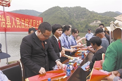 法院干警及相關部門工作人員對群眾進行生態(tài)環(huán)境保護普法教育。