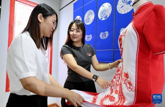 5月31日，在衡水市阜城縣一家剪紙工作室，游客在觀賞帶有剪紙?jiān)氐钠炫邸? width=