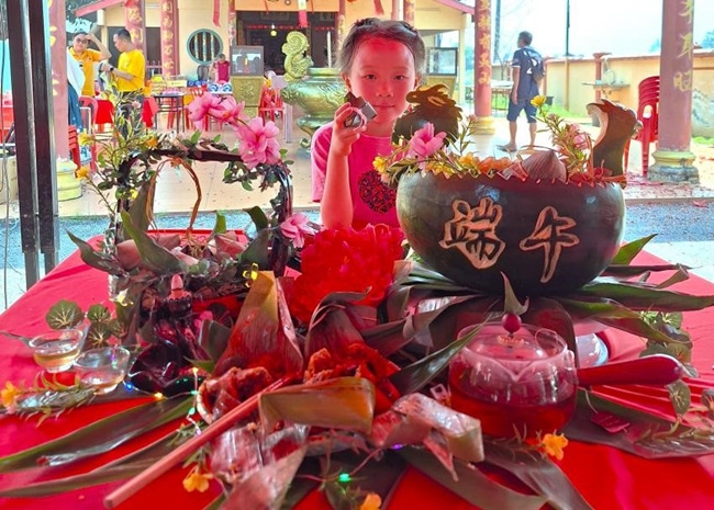 小朋友展示學(xué)裹粽子的成品照。組委會供圖