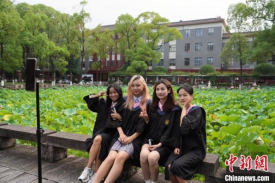 6月19日，時值一年畢業(yè)季，四川大學(xué)望江校區(qū)荷花池里的荷花盛開，成為了畢業(yè)生們的打卡圣地，吸引了眾多畢業(yè)生拍照留念。圖為畢業(yè)生在荷花池邊拍照留念。中新社記者 安源 攝