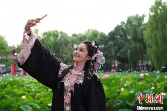 6月19日，時值一年畢業(yè)季，四川大學(xué)望江校區(qū)荷花池里的荷花盛開，成為了畢業(yè)生們的打卡圣地，吸引了眾多畢業(yè)生拍照留念。圖為畢業(yè)生在荷花池邊拍照留念。中新社記者 安源 攝