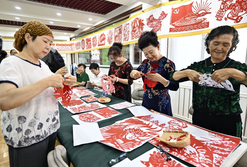 6月19日，長(zhǎng)城花園社區(qū)居民在社區(qū)“才藝堂”制作剪紙。