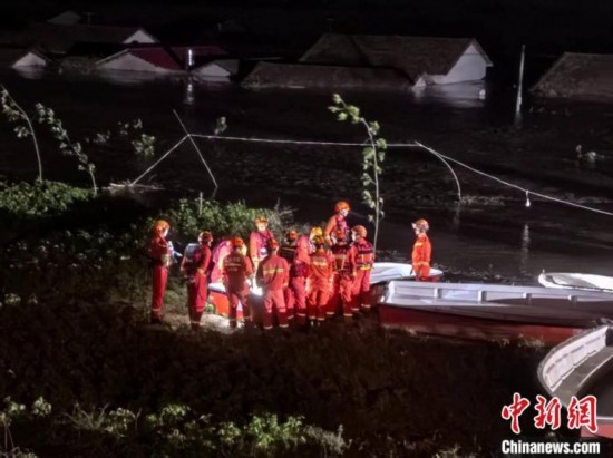  7月6日凌晨3時(shí)，在湖南岳陽(yáng)華容縣團(tuán)洲垸洞庭湖一線堤防，救援人員剛剛完成一次救援任務(wù)，遠(yuǎn)處是被淹的民房。中新社記者 白祖偕 攝