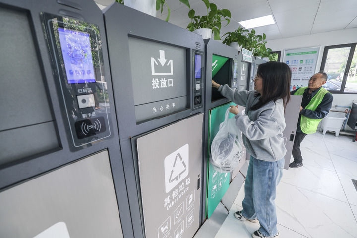 2024年4月10日，在浙江省湖州市吳興區(qū)飛英街道新華府小區(qū)內(nèi)，居民在垃圾分類智能系統(tǒng)的指導(dǎo)下進行垃圾分類投放，居民的投放情況將實時匯總到智慧服務(wù)平臺，會有相應(yīng)的積分獎勵。新華社記者 徐昱 攝