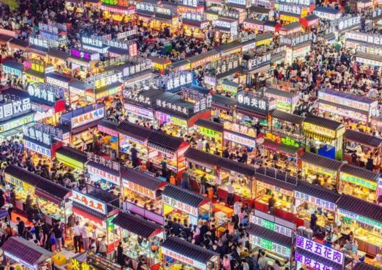 2024年4月21日，人們?cè)诤颖笔≌h小商品夜市品嘗美食（無人機(jī)照片）。新華社發(fā)（武志偉 攝）