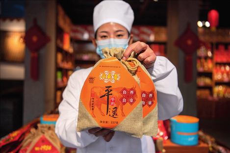 在位于山西省晉中市平遙縣的平遙古城南大街的一家平遙牛肉店內(nèi)，工作人員展示一款牛肉產(chǎn)品（資料照片）楊晨光攝 / 本刊