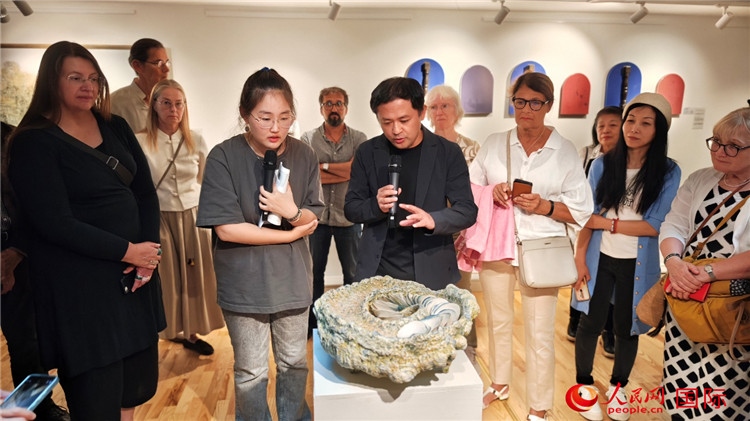 參展人、景德鎮(zhèn)陶瓷大學(xué)設(shè)計藝術(shù)學(xué)院副院長余劍峰（中）向來賓介紹參展作品。人民網(wǎng)記者 殷淼攝