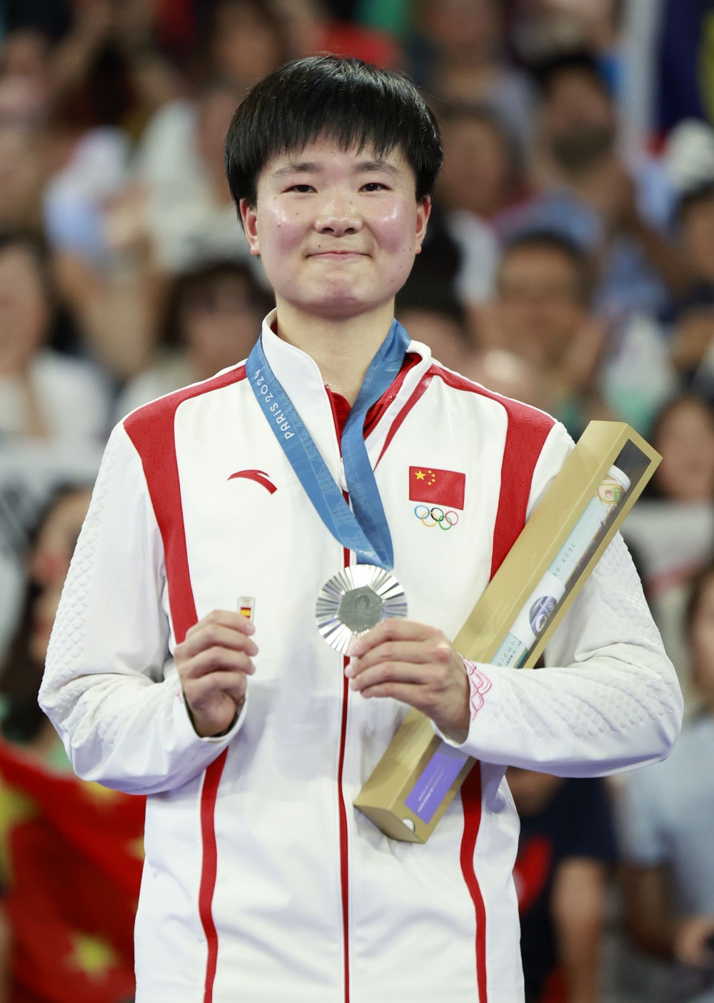 巴黎奧運會羽毛球女子單打亞軍、中國選手何冰嬌在頒獎儀式上一手握著銀牌，一手握著西班牙奧委會徽章（2024年8月5日攝）。新華社記者 任正來 攝
