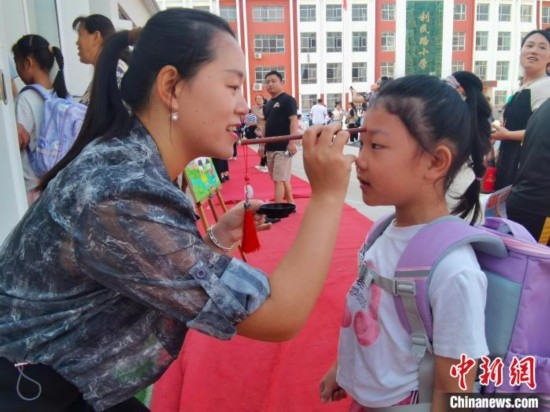 圖為衡水市利民路小學，老師為學生點朱砂痣，寓意開啟智慧。張松 攝