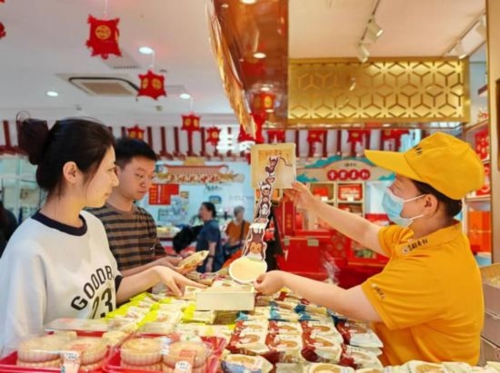 北京稻香村一家門(mén)店內(nèi)，售貨員向顧客展示新上市的月餅禮盒。（受訪(fǎng)者供圖）