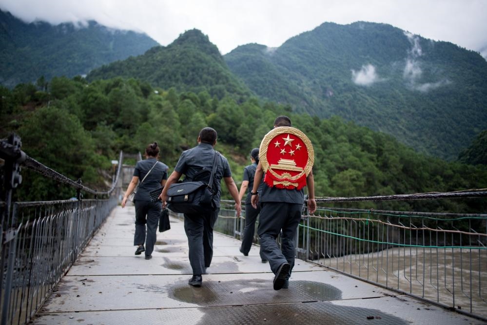 云南省怒江傈僳族自治州貢山縣人民法院法官鄧興背著國徽與同事們跨過怒江（2019年8月30日攝）。怒江高山峽谷眾多，交通不便，為方便群眾、更好地開展法律服務，背著國徽攀高山、過索橋、躲落石、鉆老林……成為鄧興法官的工作常態(tài)。新華社記者 江文耀 攝