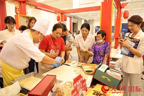 演出前，在天津桂發(fā)祥十八街麻花制作技藝非遺體驗(yàn)展臺(tái)前，泰國(guó)民眾體驗(yàn)天津麻花制作。人民網(wǎng)記者 楊一攝