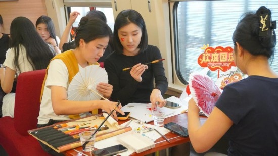 10月1日，旅客們?cè)贕1634次列車上給油紙傘作畫。新華社記者周義 攝
